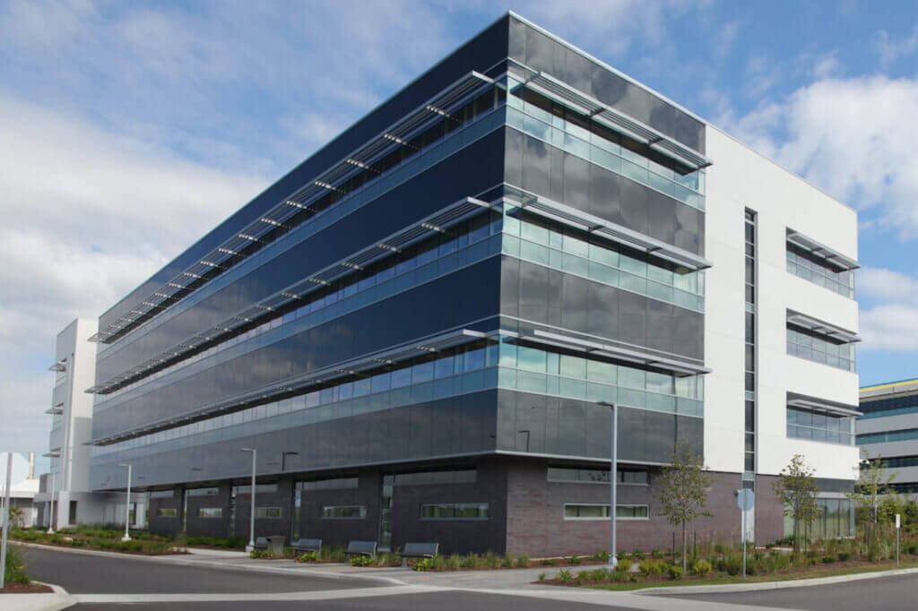 A large glass building with a brick bottom and white and black trim