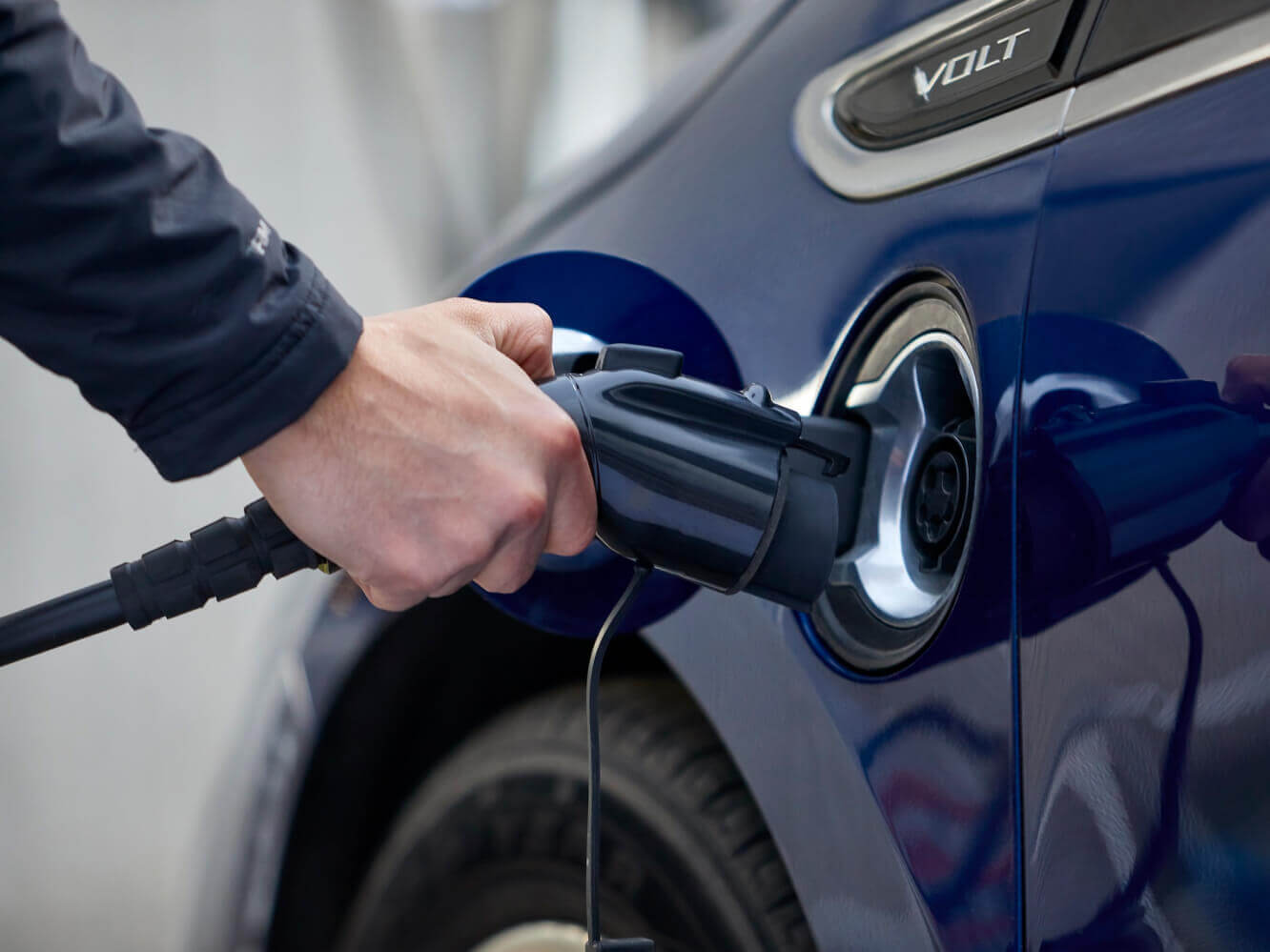 A man holding the end of an EvoCharge charger, about to hook it up to the charging port on his car