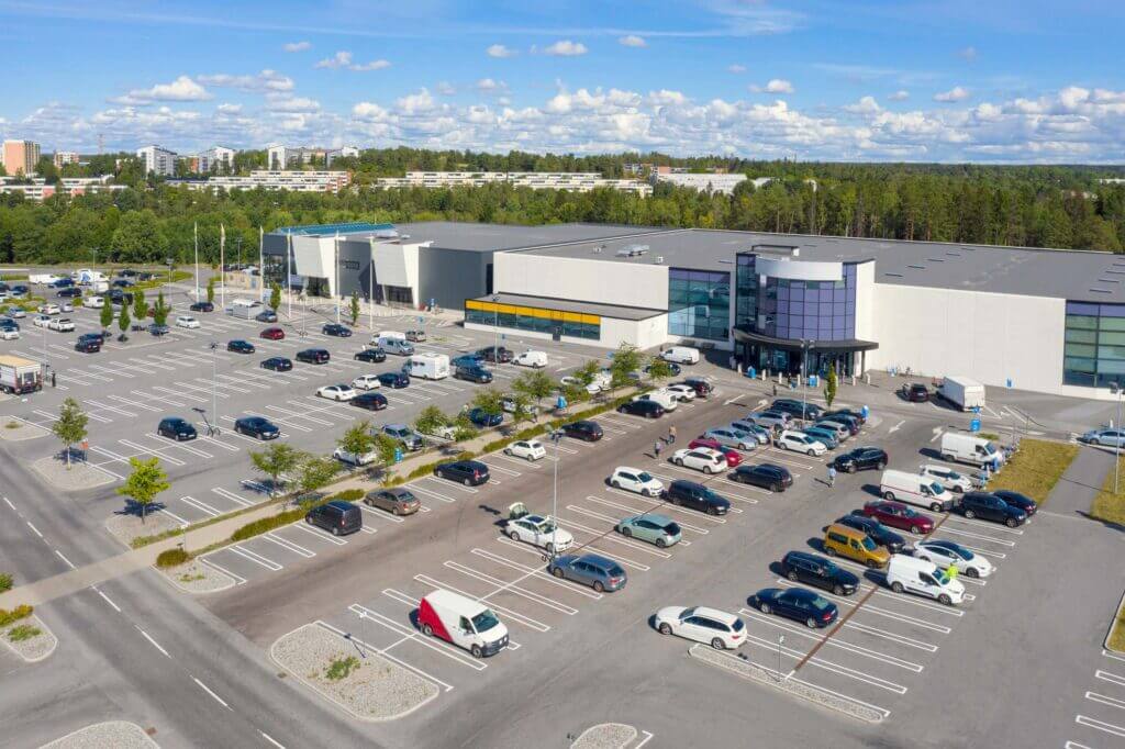 A partially filled parking lot adjacent to a retail center during the daytime.