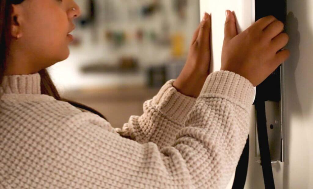 Closeup of a woman installing an EVSE in a garage.